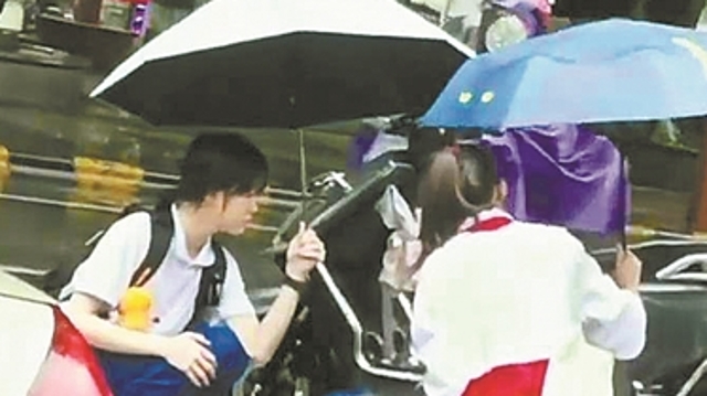 韶关：市民雨中骑车摔倒 初中生“跪地撑伞”