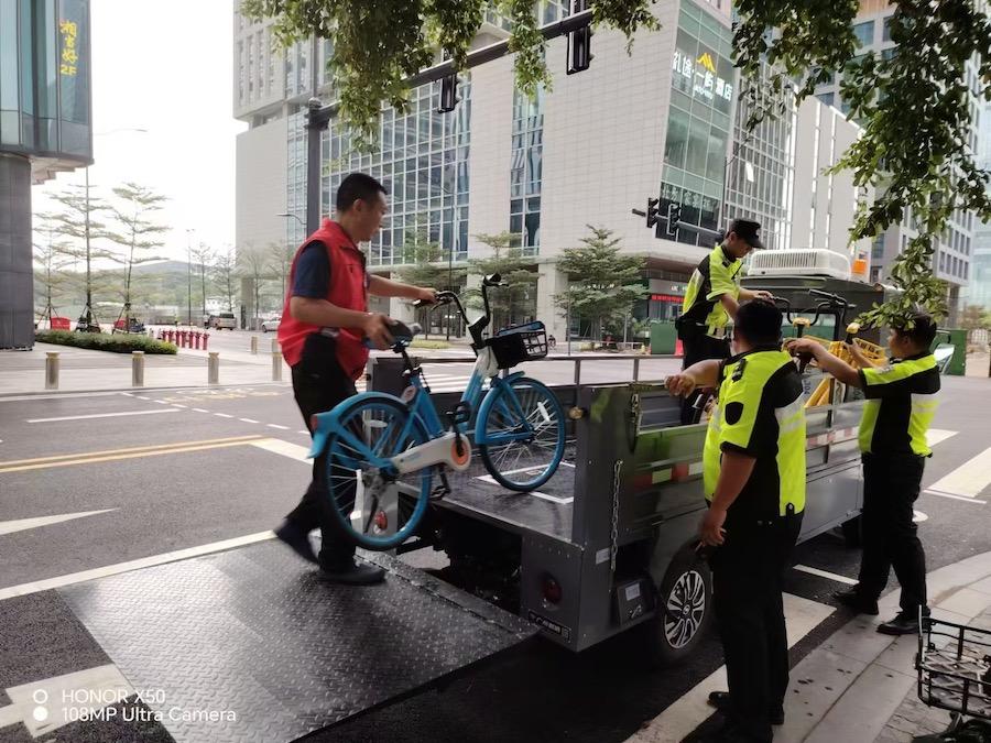 志愿者与交通整治服务队队员一起将共享单车和电动自行车运往停放点1